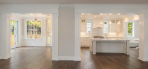 Spacious open-plan kitchen and dining area with white cabinetry, pendant lights, hardwood floors, and large windows, creating a bright, inviting atmosphere.